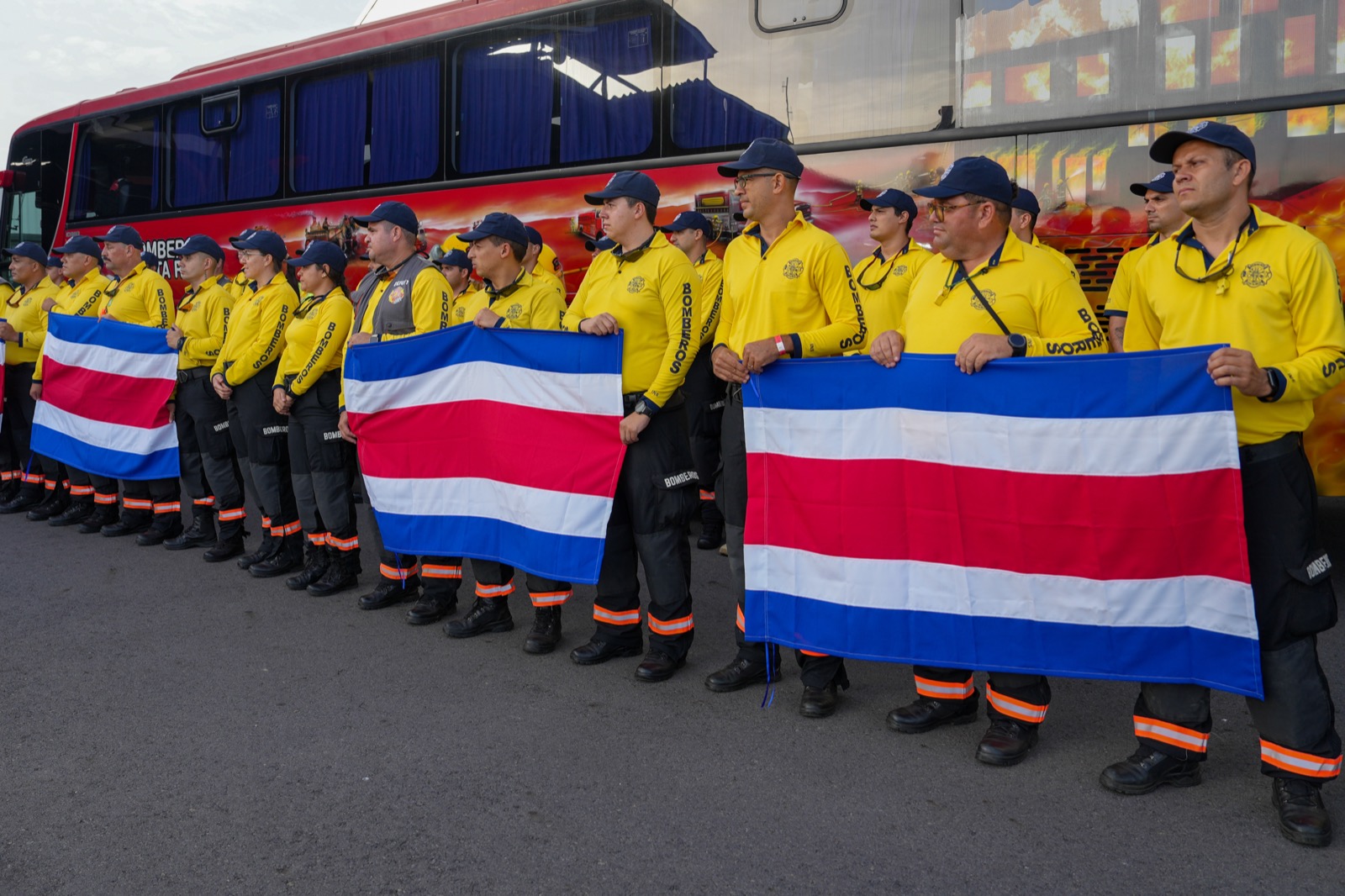 Bomberos de Costa Rica en fila con banderas de su país, antes de partir hacia Venezuela para las labores de rescate